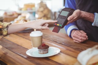 Customer entering pin number into machine at counter in cafe