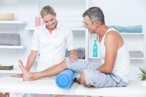 Doctor examining her patient leg in medical office