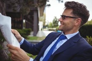 Handsome businessman reading newspaper outside office