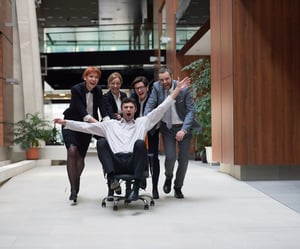 business people group at modern office indoors have fun and push office chair on corridor