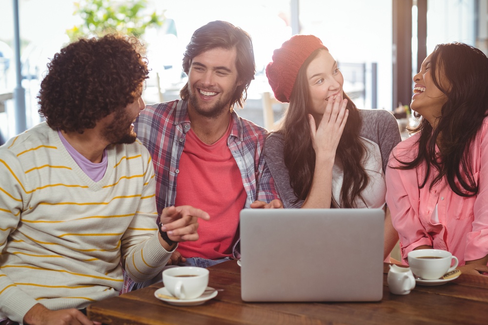 Laughing friends enjoying coffee with laptop in cafe.jpeg